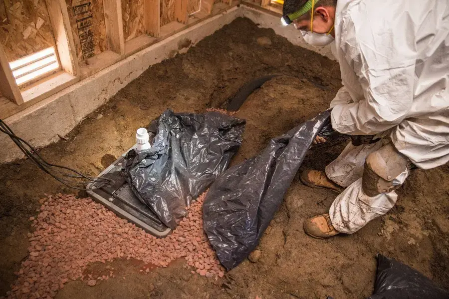 Technician in protective gear bagging debris in a crawl space in Walnut Creek
