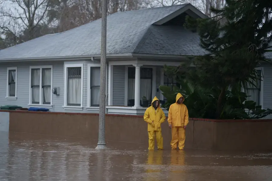 Floodwater standing in front of a single-story home during a storm